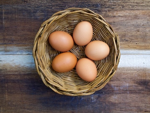 Photo eggs in basket on wooden background, top view