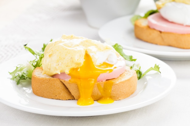 Eggs benedict close-up op witte plaat, serveertafel