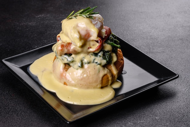 Eggs Benedict of Eggs Florentine op een zwarte plaat in het café. Egg Benedict op geroosterde Engelse muffin