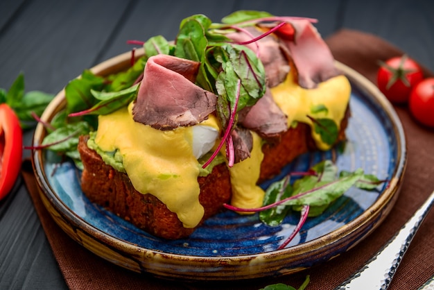 Uova alla benedict su pane tostato con prosciutto e salsa. prima colazione al ristorante