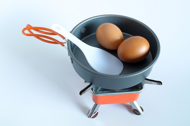 Eggs in camping pan on stove for cooking.