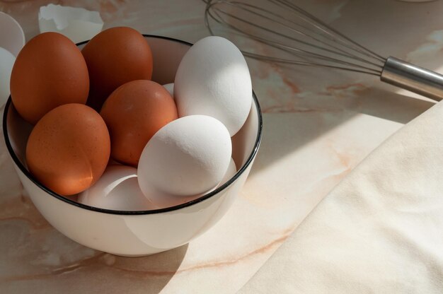 Eggs in a ceramic cup closeup Cooking in the kitchen White and brown eggs Sunny morning Preparing breakfast selective focus