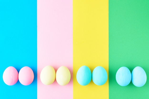 Eggs on colored striped background, top view, minimalism concept
