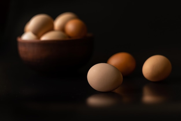 Eggs of different shades in a bowl on a black background