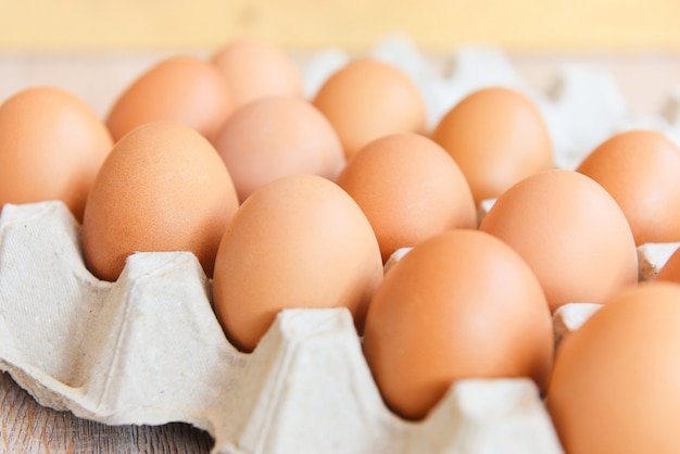 Eggs in egg box on wooden background / Close up of raw chicken eggs organic food