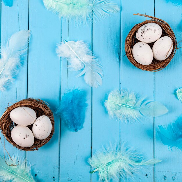 Eggs and feathers on a blue wooden background. Easter still life.