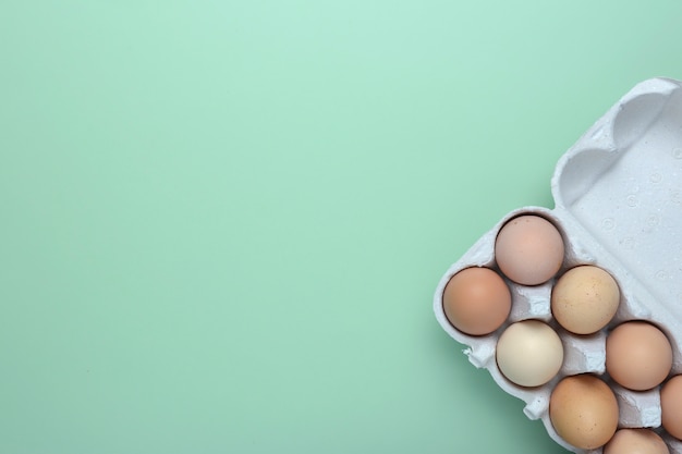 Eggs flat lay. Chicken eggs in cardboard box over green background. Egg top view.