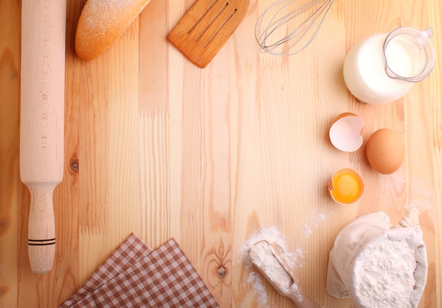 Eggs flour milk and whisk on a wood background