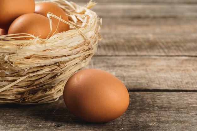 Eggs in the hay nest on wooden table