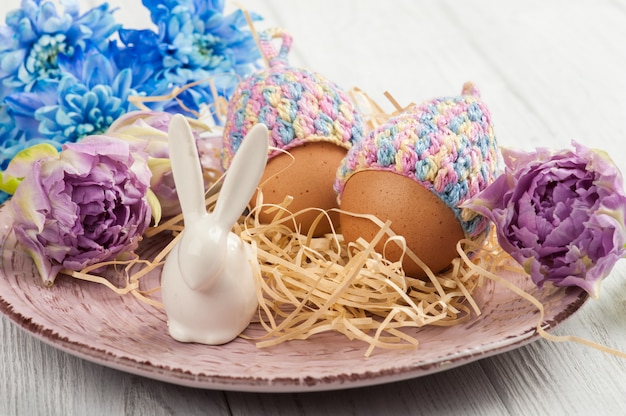 Eggs in knitted hats, flowers and decorative rabbit 