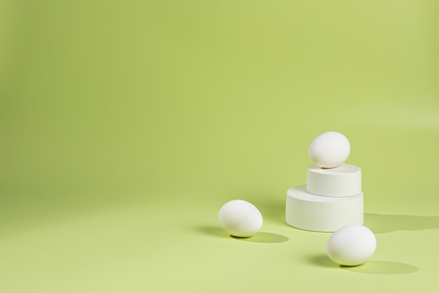 Photo eggs lie on a pyramid of white podiums on a green background with a shadow from sunlight