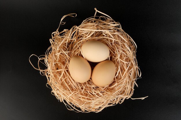 Photo eggs in a nest basket on black background