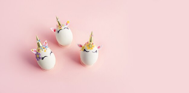 Eggs painted with unicorn theme over pink surface. Easter concept