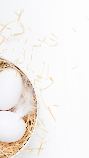 Eggs in a round box with hay on white.