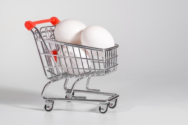 Eggs in a shopping cart a closeup at the white background a notion of shopping