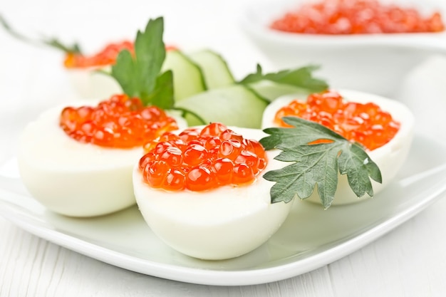 Eggs stuffed with caviar on a white wooden board