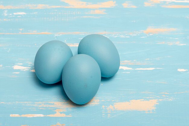 Яйца, символизирующие праздник Пасхи, синего цвета на фоне состаренного дерева