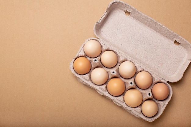 Eggs tray on brown background, copy space, top view.