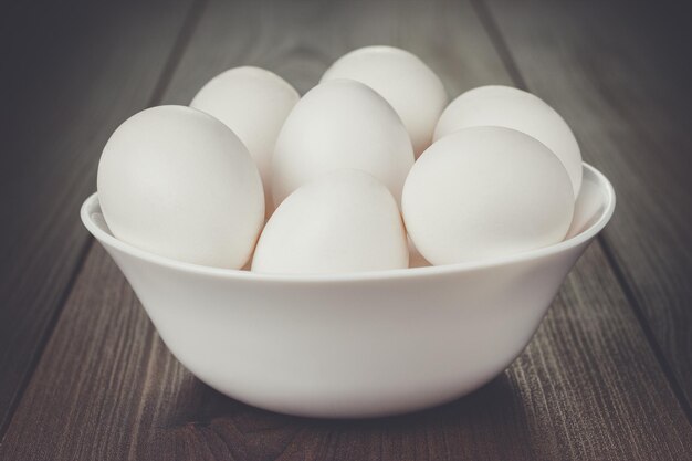 Eggs in white bowl on wooden table