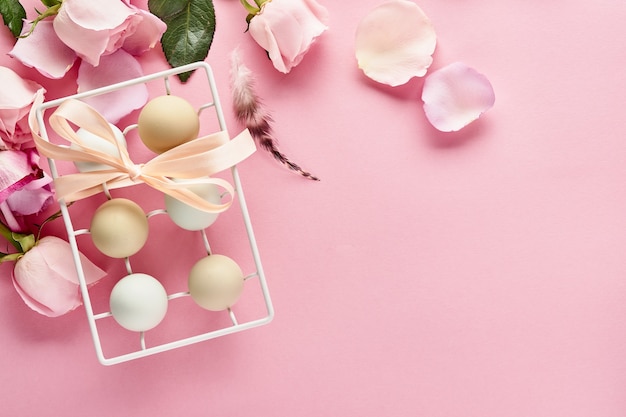 Eggs in white ceramic holder and flowers on pink background. Top view.