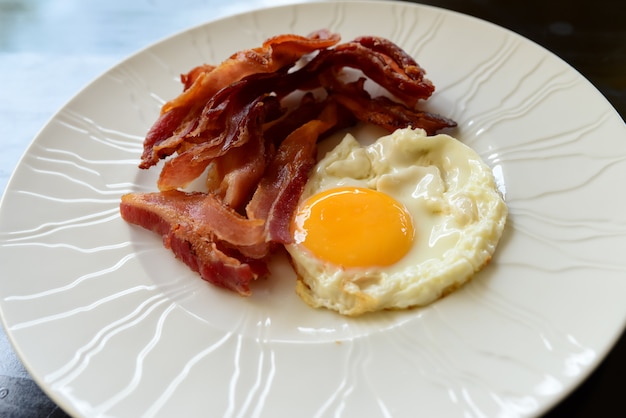 Foto uova con pancetta per la colazione sul piatto bianco