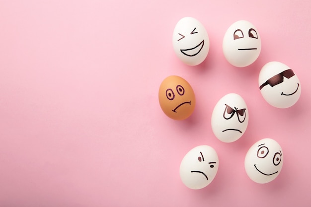 Eggs with different emotions on his face. Easter composition with copy space on pink background.