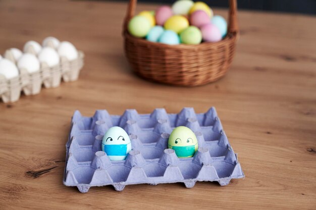 Eggs with face masks in a cardboard box on the table