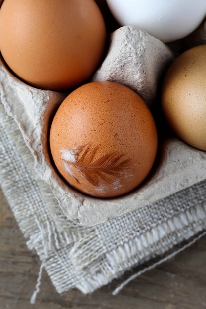 Photo eggs with feather inside paper container on jute towel