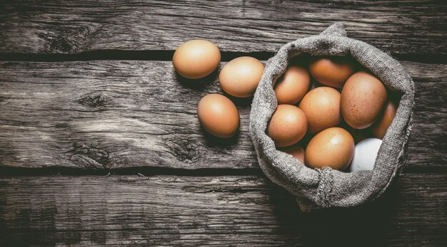 Eggs with an old bag on wooden table. Top view