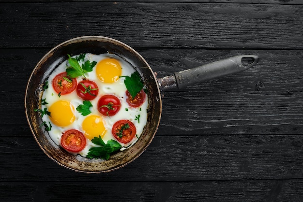 Eggs with tomatoes and greens in a frying pan