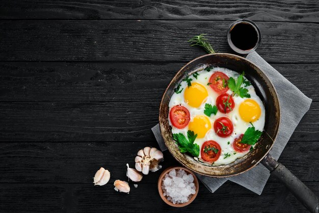 Eggs with tomatoes and greens in a frying pan