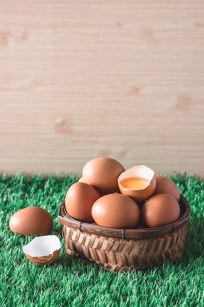 Eggs in wooden basket on green grass.