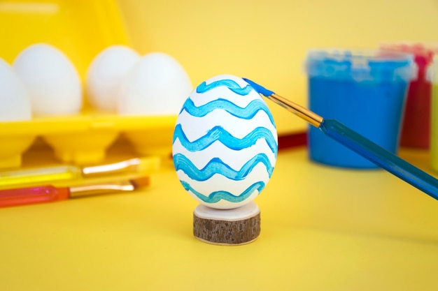 Foto uova in vassoio giallo per uova, colori colorati e pennelli per decorare le uova per le vacanze. attività familiare, preparazione creativa alla buona pasqua.