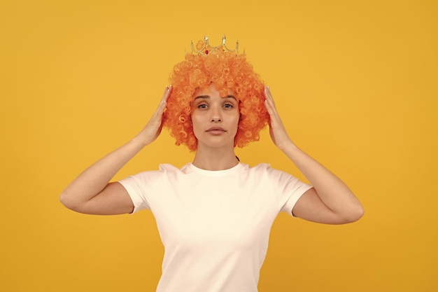 Egoistic funny girl with fancy look wearing orange hair wig and princess crown egoist