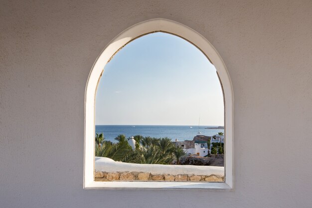 Egypt. A look through the frame on the palm trees. Beautiful view. White house and veranda overlooking the sea and palm trees. Sea view from the room