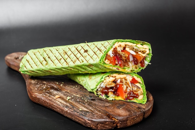 Egyptian shawarma in green pita bread with fried meat and vegetables on a wooden cutting board