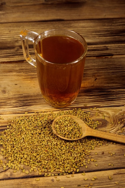 Egyptian yellow tea or Methi Dana drink and fenugreek seeds on wooden table