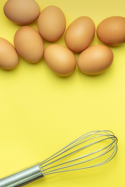 ei en eierklopper op gele achtergrond Kippeneieren bruine eieren gebroken ei in kartonnen doos