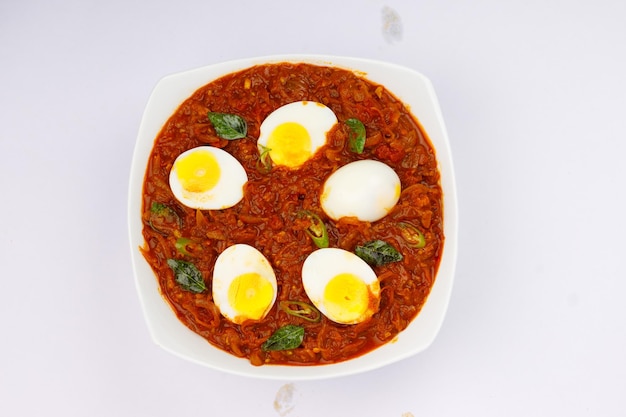 Ei gebraden of Indiase ei masala curry pittig rood ei gebraden in een witte keramische kom