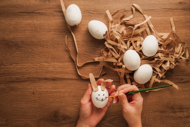 ei in de hand als een konijnengezicht en ander wit ei op houten tafel