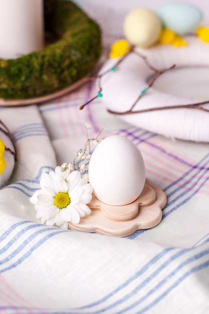 Ei in een houten standaard met florale elementen - elementen van de feestelijke tafel van Pasen, serveert optie