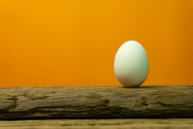 Ei op een oude eiken houten tafel met oranje achtergrond