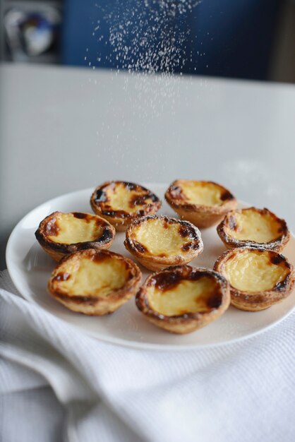 Ei taart traditioneel Portugees dessert pastel de nata pasteis op een plaat grijze stenen achtergrond