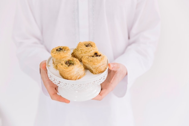 Foto eid al-fitr concept met de mens die arabisch gebakje voorstelt