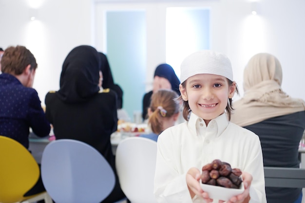Eid Mubarak Moslimfamilie die Iftar-diner heeft kleine jongen die een bord vol zoete dadels vasthoudt om het feest te breken. Thuis traditioneel eten eten tijdens de Ramadan-feestmaand. Het islamitische halal eten en