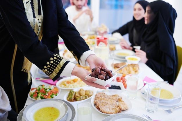 Eid Mubarak Muslim family having Iftar dinner eating dates to break feast. Eating traditional food during Ramadan feasting month at home. The Islamic Halal Eating and Drinking at modern western Islam