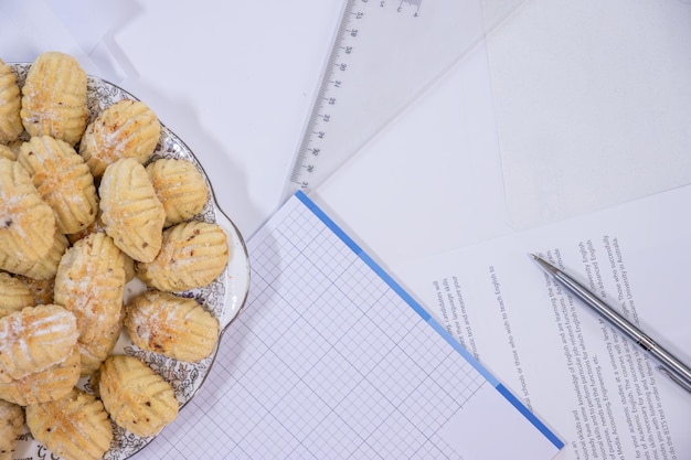 Eid sweets with hand clock on desk full of working papers