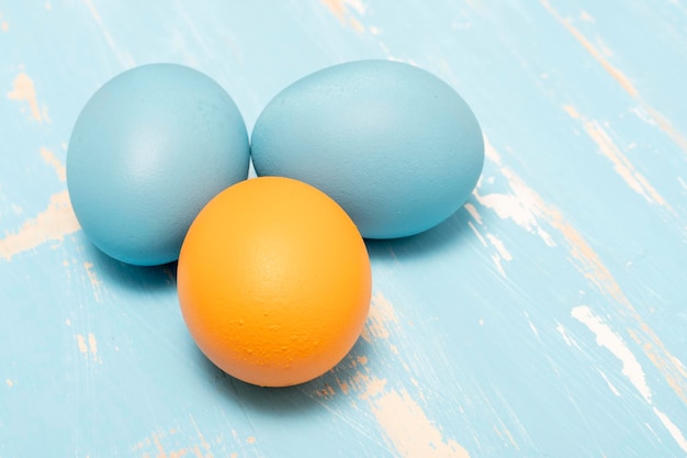 Eieren die de paasvakantie symboliseren in blauwe en oranje kleur op een achtergrond van oud hout