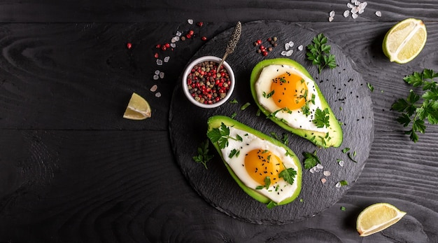 Eieren gebakken in avocado verse rucola gemalen peper op donkere achtergrond Low carb hoog vet ontbijt bovenaanzicht