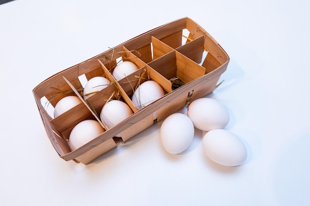 Eieren in de houten kist in het hooi op de witte achtergrond Gezonde voeding concept
